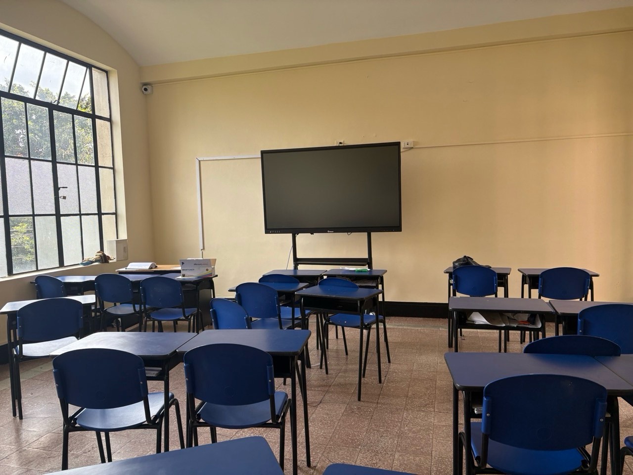 Aula amplia con ventanal y pantalla interactiva al frente