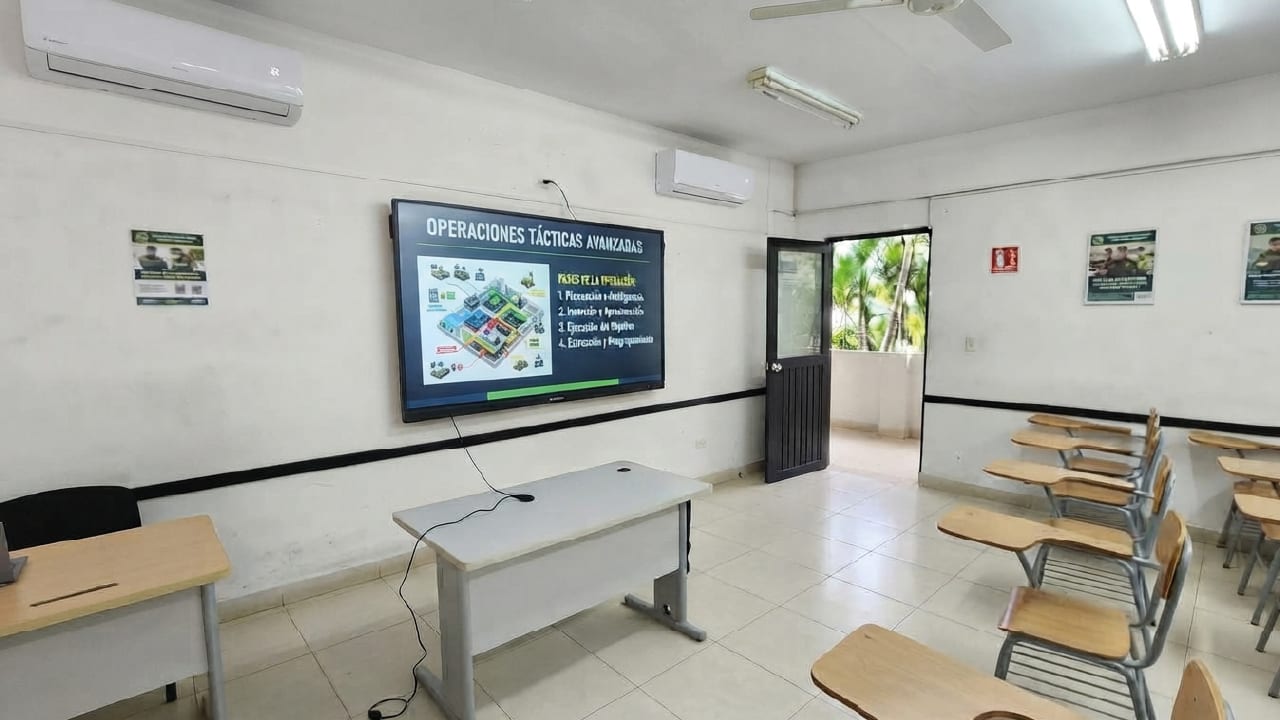 Aula de formación de la Policía Nacional con la pantalla interactiva al frente y pupitres en filas