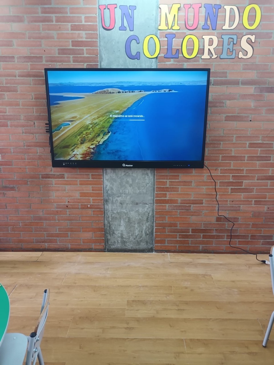 Pantalla interactiva QMaster en muro de ladrillo de un aula de preescolar