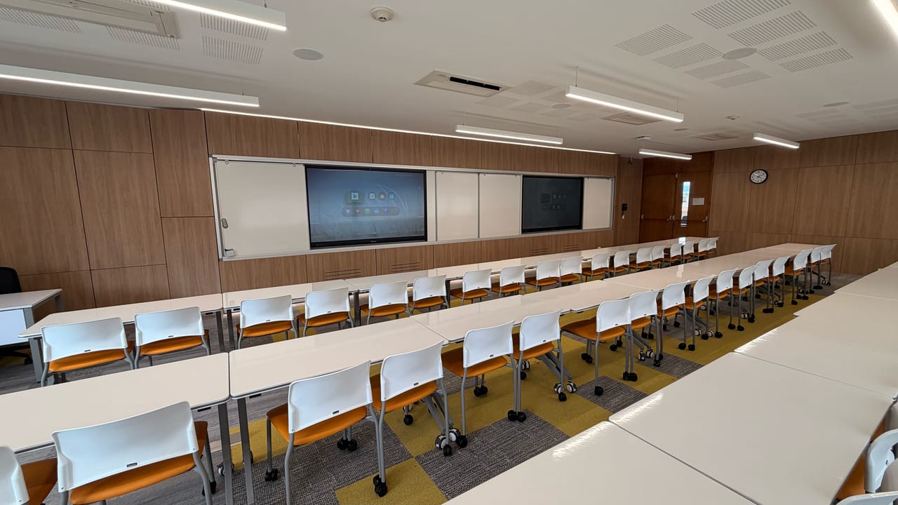 Aula de práctica de la Universidad de los Andes con dos pantallas interactivas empotradas y encendidas